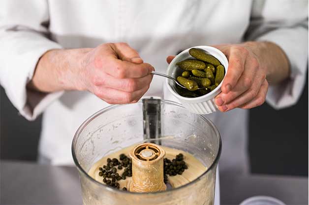 Chef adding pickles to the mayonnaise