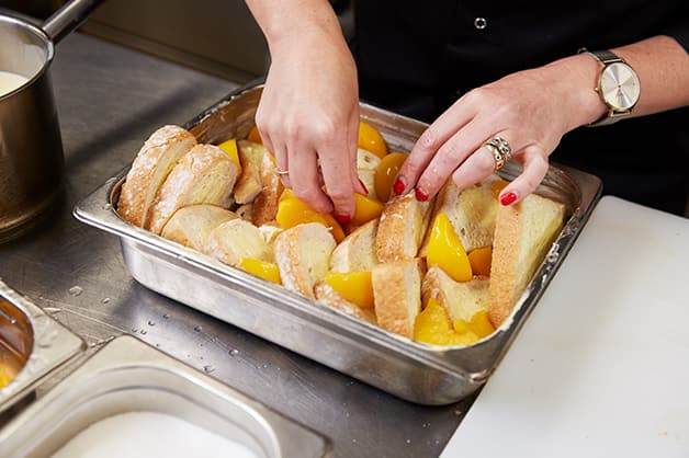 The chef is placing the peaches inbetween the slices of bread