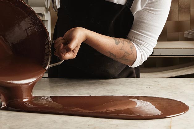 Image shows a chef tempering chocolate