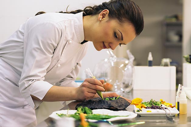 This picture shows a female chef plating a meal