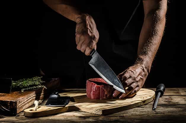 The image shows a chef using the knife