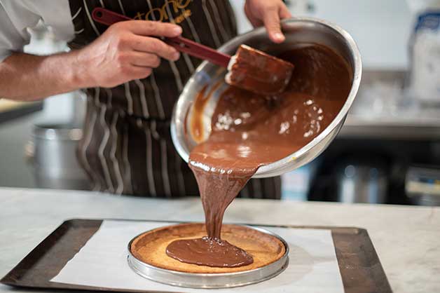 Pouring melted chocolate into baked tart shell