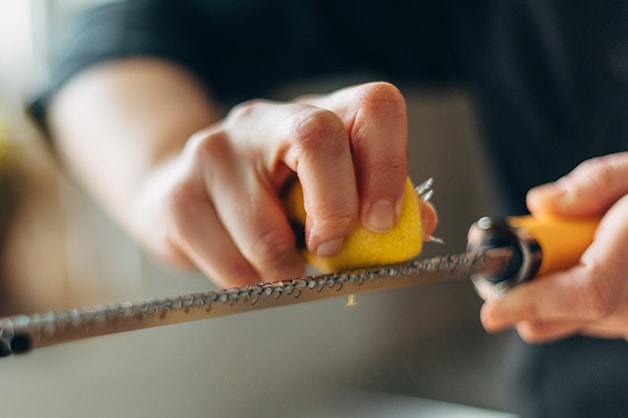 Chef is seen grating a lemon on a microplane