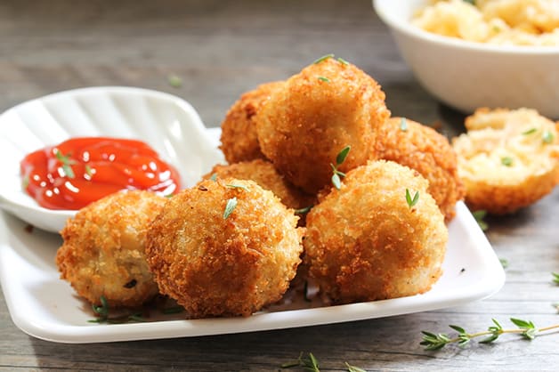 Image shows golden fried croquettes next to sauce