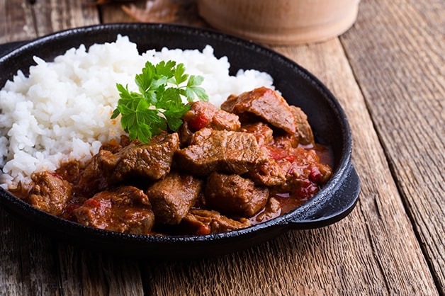 Beef stew with rice can be seen in this image