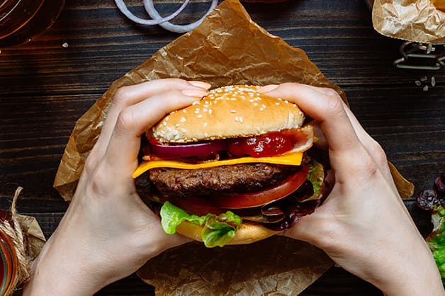 Image of a person holding a burger with both hands