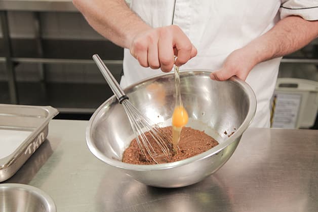 Adding an egg to the brownie mix
